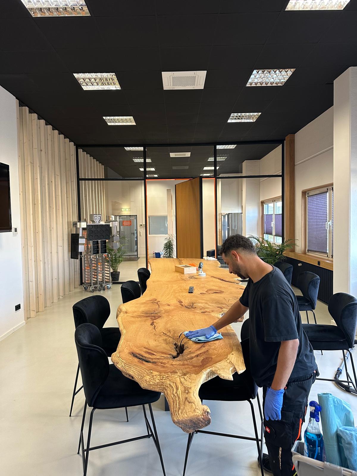 Reinigung eines großen Holztischs in einem modernen Konferenzraum